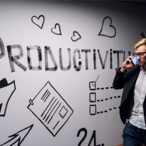Operations consultant walking past wall that says 'productivity'