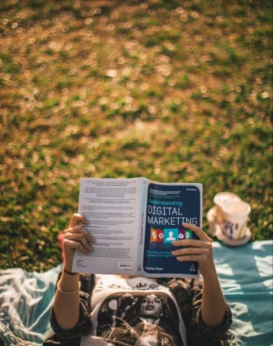 Human reading a digital marketing book in a park